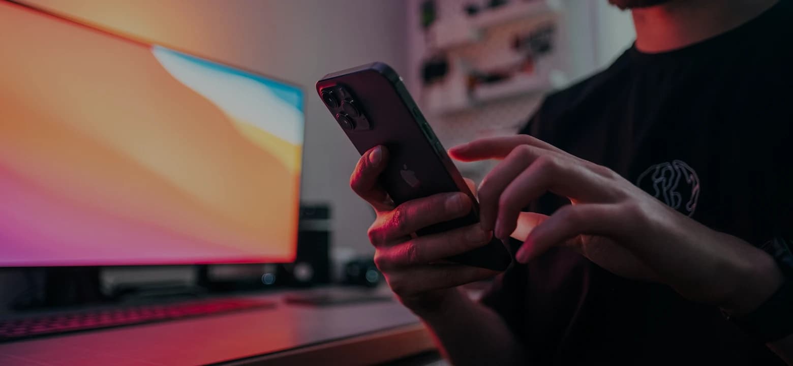 Une personne utilise un téléphone à un bureau, devant un écran
